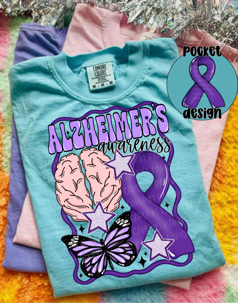Light blue t-shirt with Alzheimer's awareness design featuring brain, butterfly, and purple ribbon on a colorful fabric background.