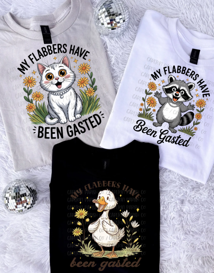Three shirts with animal-themed designs and text on a fluffy white surface.