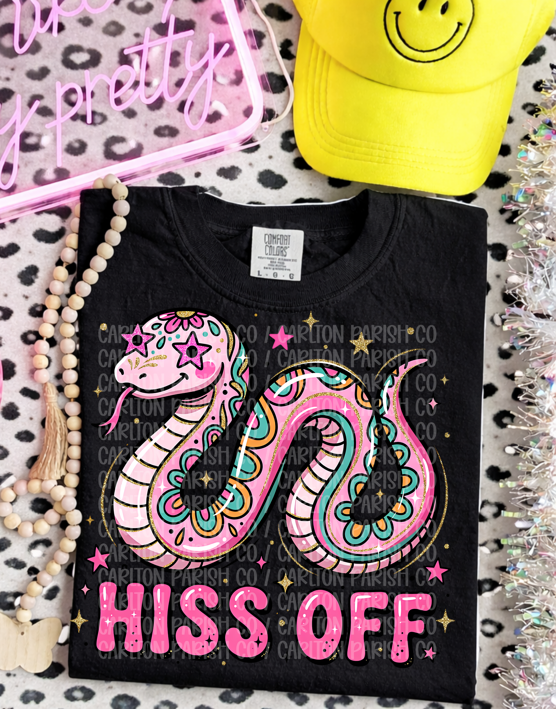 Black t-shirt with colorful snake design and 'Hiss Off' text on a patterned surface.