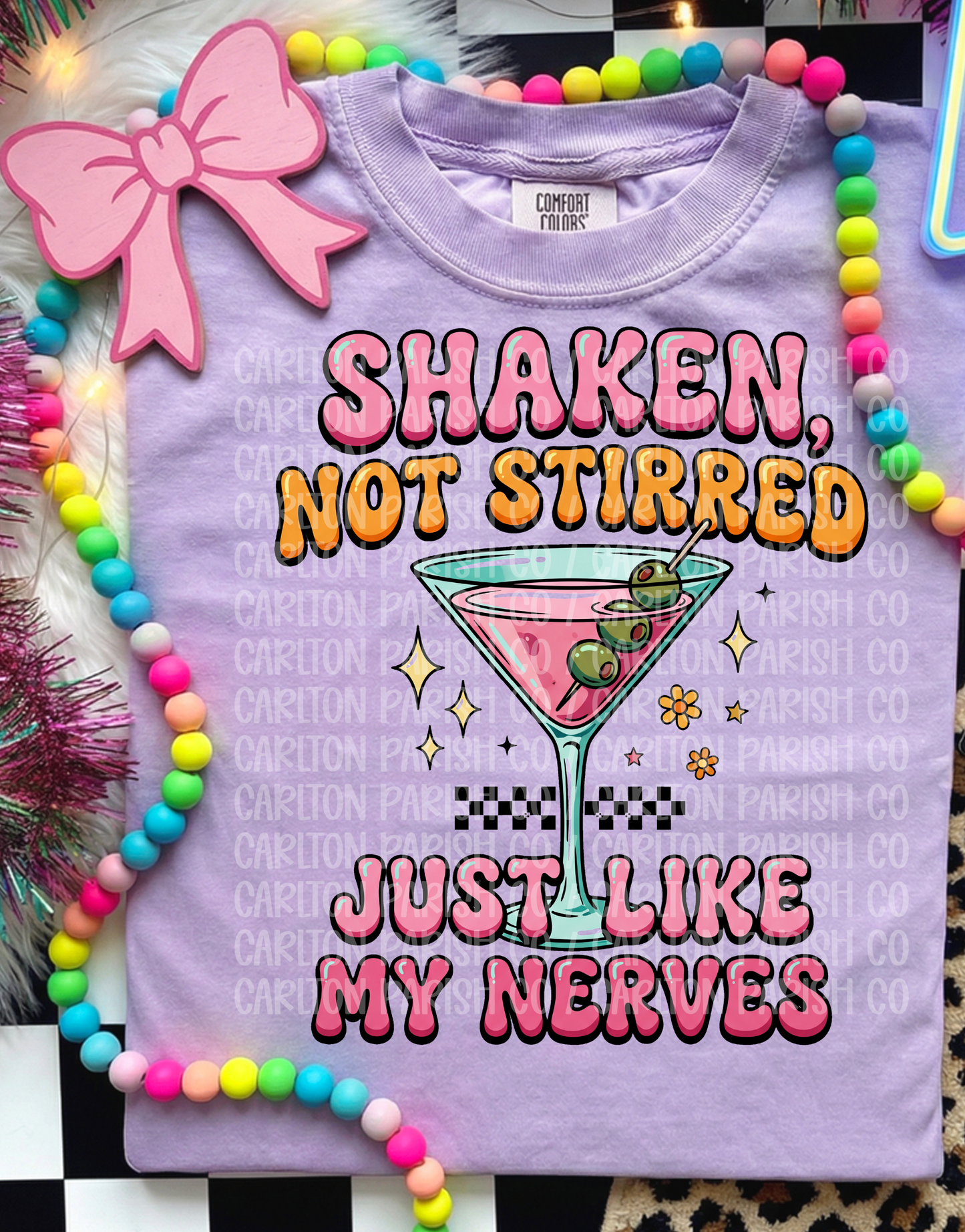 Purple t-shirt with cocktail graphic and text 'Shaken, Not Stirred Just Like My Nerves' on a colorful background.